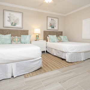 Rest comfortably in this guest bedroom with two queen beds, decorative pillows, and soft lighting