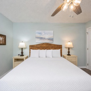 The king suite offers a cozy bed framed by soft lamps and calming coastal wall art