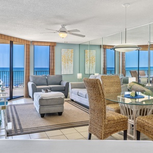 Bright living area featuring a comfortable gray sofa with queen sleeper, dining table with chairs, and a stunning beach view