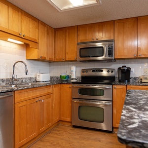 Warm wood cabinetry complements the granite countertops in this kitchen, featuring modern stainless appliances