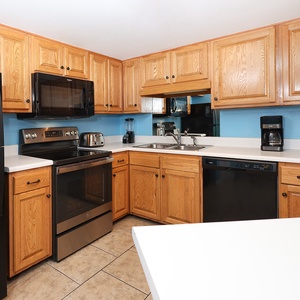 Kitchen features oak cabinetry, a breakfast bar, and a blend of black and stainless appliances, perfect for vacation meals