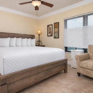 Inviting guest room with a comfortable king bed, cozy chair, and a view of the surrounding area through large windows