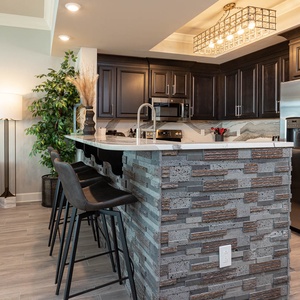 Savor morning coffee at the stone-front bar or prepare meals in this elegantly-designed kitchen