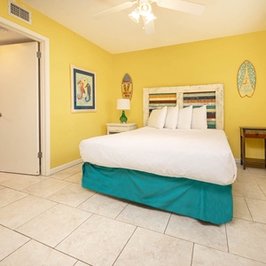 Bright yellow walls complement this guest bedroom featuring a queen bed, colorful headboard, and charming decor