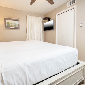 A comfortable bedroom features a king bed, a wall-mounted TV, and soft lighting for a relaxing atmosphere