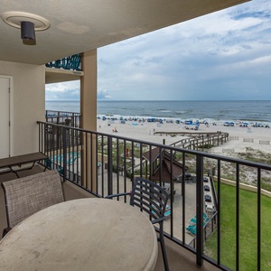 Relax on the balcony with a view of the beach, featuring comfortable seating and a table for enjoying meals outdoors
