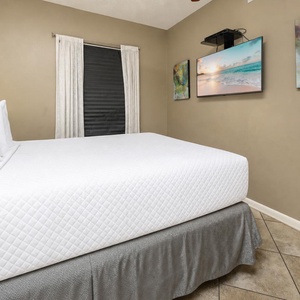 Comfortable guest bedroom featuring a plush queen bed, soft lighting, and a TV for your entertainment
