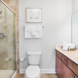 This bathroom features a glass walk-in shower, elegant cabinetry, and neatly arranged towels for a refreshing experience