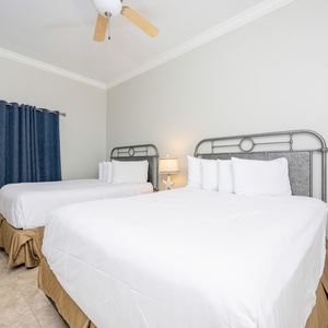 Rest comfortably in this inviting guest room featuring two queen beds, soft linens, and a bedside lamp