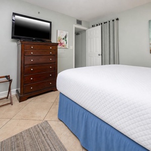 This cozy guest bedroom features a queen bed, a flat-screen TV, and a charming artwork, perfect for a relaxing stay