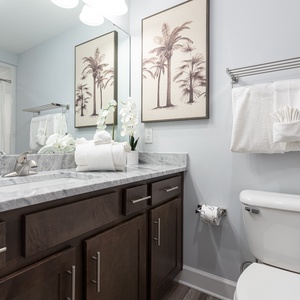 Admire palm artwork beside the mirror and freshen up before your day at the beach in this guest bath
