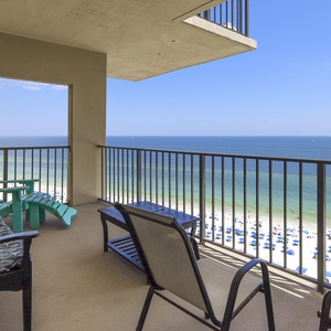 Relax on the balcony with turquoise chairs, enjoying breathtaking views of the sandy beach and vibrant blue waters