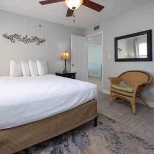 This guest bedroom features a queen bed, stylish decor, a flat-screen TV, and a charming wicker chair for relaxation