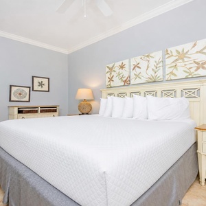 Cheerful guest bedroom featuring a plush king bed, coastal decor, and warm lighting for a serene retreat