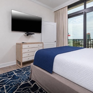This bedroom features a cozy design with a TV mounted on the wall and a stunning beachfront view through large windows