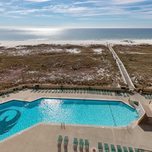 Inviting pool area with ample lounge chairs, leading to a serene beach just steps away, perfect for relaxation and fun