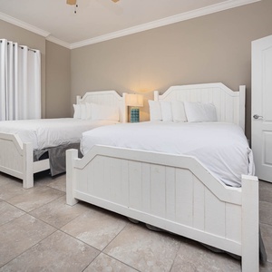 Rest in the cozy guest room with two queen beds, where soft light sets the perfect mood for restful sleep