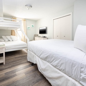 Relax in this guest bedroom featuring a queen bed, bunk beds, and a TV
