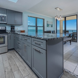 Bright modern kitchen with stainless appliances and a stunning view of the coastline from the dining area