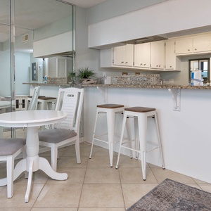 Inviting space featuring a breakfast bar and stools, white dining set, and stylish decor with playful flamingo art