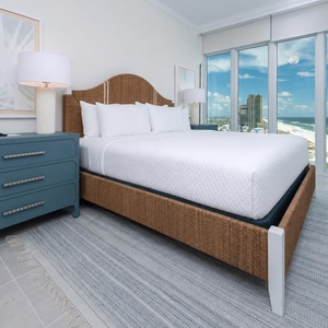 Relax on the cozy king bed in this guest suite and discover stunning beach views