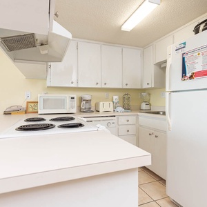 This kitchen features white cabinetry, a smooth cooktop, and essential appliances for a convenient cooking experience
