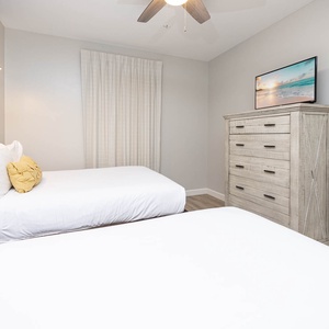 Inviting guest bedroom featuring two comfortable double beds, a stylish dresser, TV, and soft lighting