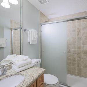 Guest bathroom featuring a spacious vanity with granite countertops, fresh towels, and a glass-enclosed walk-in shower