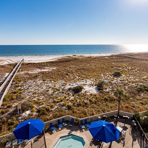 Stunning gulf view showcases a serene beach with white sand, framed by a lush landscape and inviting pool area below