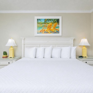 Sleep soundly in this guest room featuring a king bed, coastal artwork, and cheerful lamps for a relaxing retreat