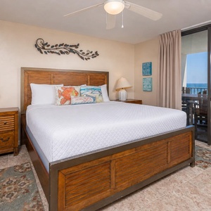 Master bedroom featuring a king bed, colorful pillows, a ceiling fan, and sliding doors leading to a balcony with gulf views
