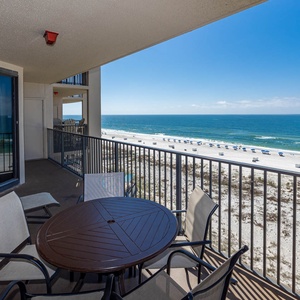Relax on the balcony with a table and chairs, enjoying views of the beach and gentle waves
