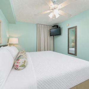 Retreat to the tranquil bedroom featuring a king bed, soothing teal walls, and a TV for your entertainment