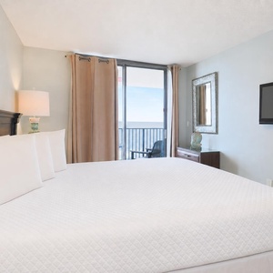 Experience restful nights in this inviting master bedroom, featuring a king bed, stylish decor, and beach balcony access
