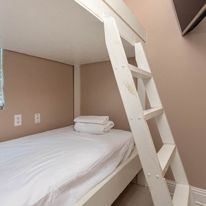 This cozy nook features a twin bunk bed with fresh linens and a mounted TV, perfect for a restful retreat