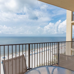 Enjoy the tranquil beachfront view from the balcony, featuring a glass table and lounge chairs for relaxation