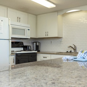This kitchen features sleek white cabinetry, granite countertops, and modern appliances for a delightful cooking experience