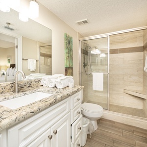 Marble countertop gleams as you prepare for the day in your bathroom with a glass walk-in shower