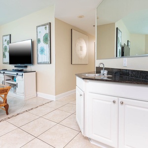 The living area features a TV, a stylish wet bar, and vibrant turquoise seating, perfect for relaxation and entertainment