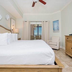Relaxing master bedroom featuring a plush king bed, a cozy armchair, and a view of the serene coastline