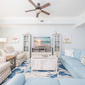 Soft and airy living room featuring a cozy blue sectional with queen sleeper, stylish decor, and a large TV