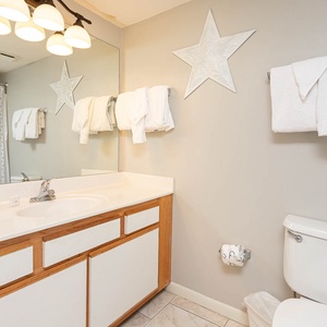 Bright guest bathroom featuring a large mirror, light fixtures, and neatly arranged towels for a fresh and welcoming vibe