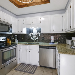 This kitchen features sleek stainless appliances, granite countertops, and a cozy coffee maker for your convenience