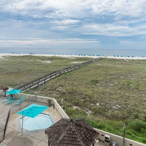Relax by the pool area with turquoise loungers, overlooking the lush greenery leading to the beach and tranquil gulf waters