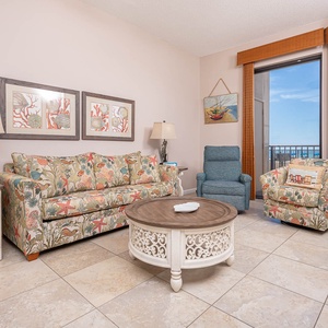 Relax in the inviting living area with a floral sofa with queen sleeper, decorative coffee table, and beachfront views