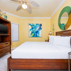 Relax in this inviting guest bedroom featuring a comfortable queen bed, a TV for entertainment, and cheerful yellow walls