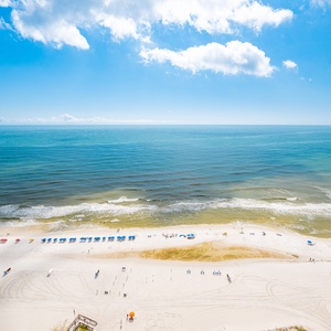 Breathtaking view of a pristine beach with colorful umbrellas under a bright blue sky, inviting relaxation and fun