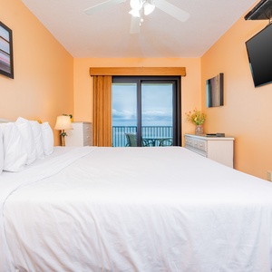 Brightly colored room featuring a king bed, a mounted TV, and balcony access with a view of the beach front