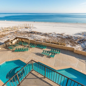 Enjoy the inviting pool area with lush green loungers, just steps away from the serene beach