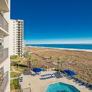 Balcony view showcasing the pool area and expansive beach front with soft white sand and vibrant blue Gulf waters